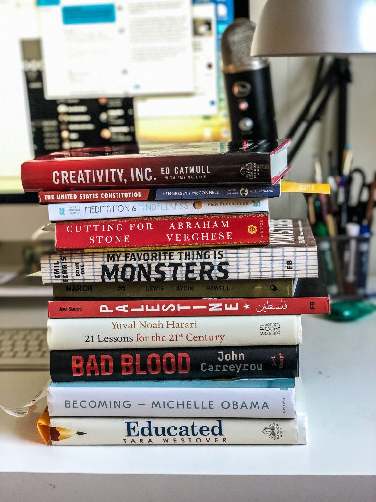a stack of books resting on a desk.